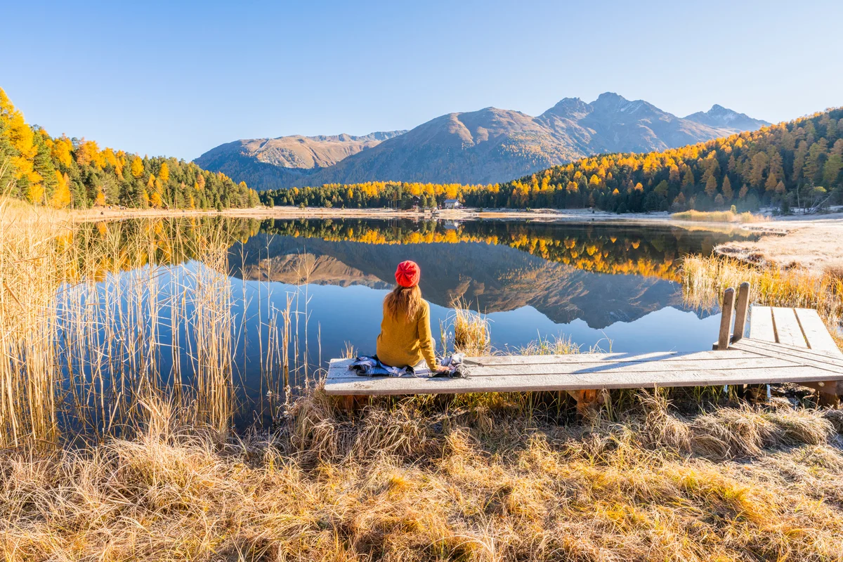 woman sitting by a lake in autumn