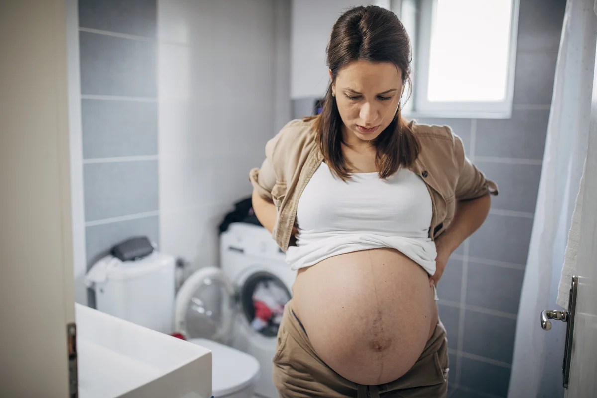 Pregnant woman looking uncomfortable in bathroom