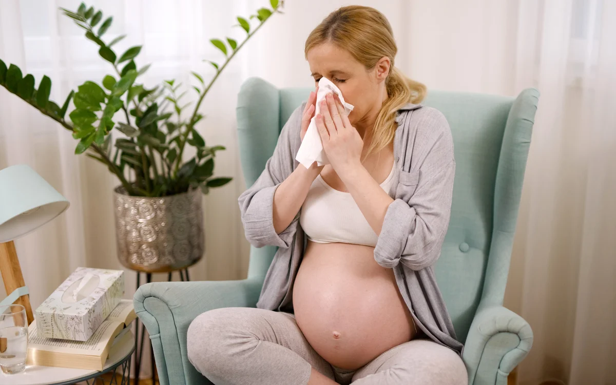 Pregnant woman holding tissue to nose