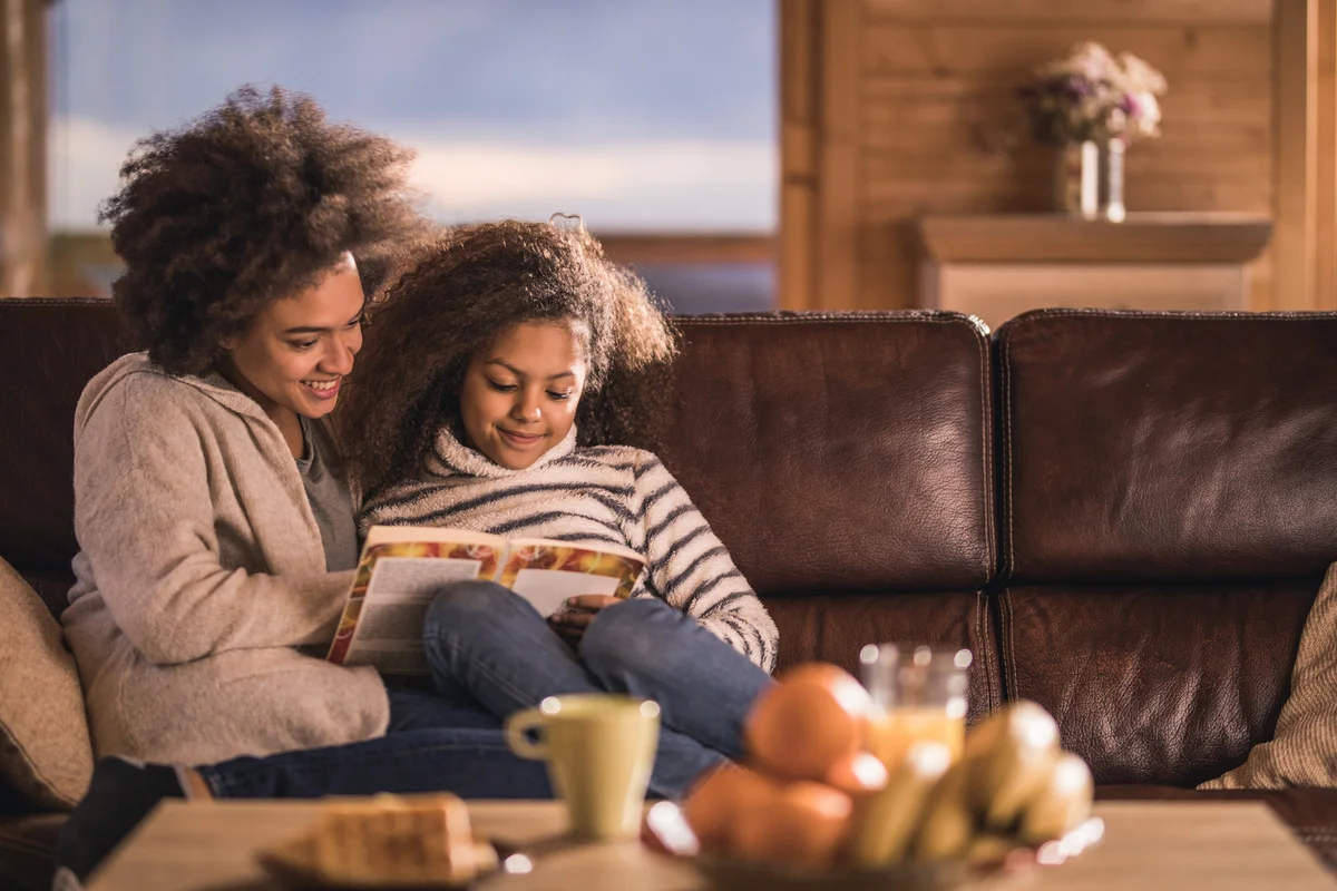 Mom and daughter snuggled up and reading a book in autumn time