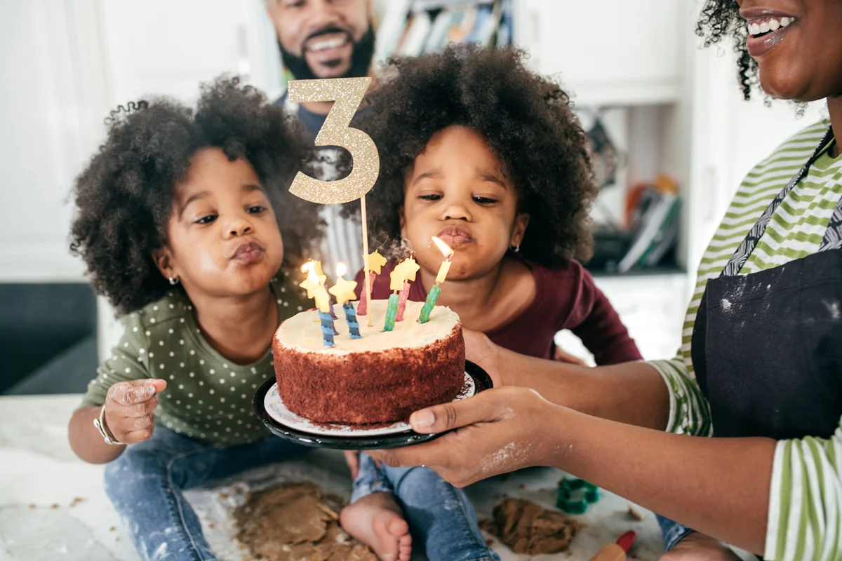 Family celebrating twins birthday with cake and candles