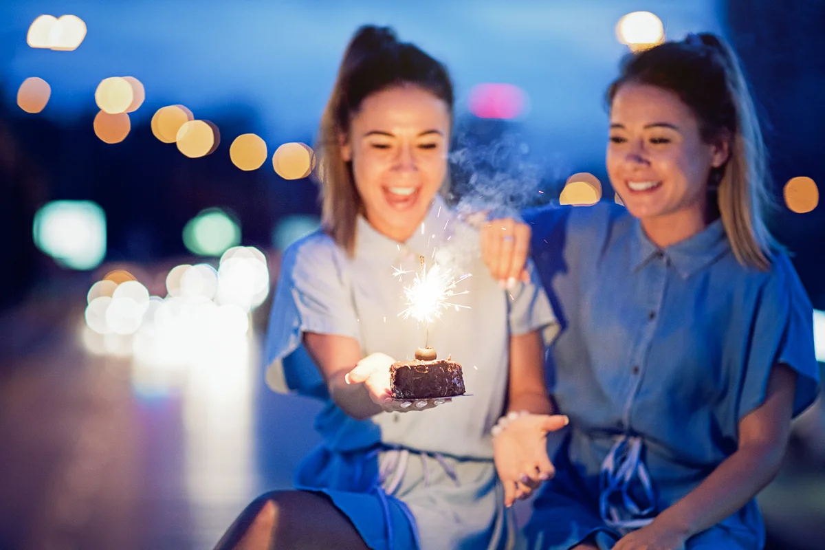 Twin sisters are celebrating their birthday with a cake and candle