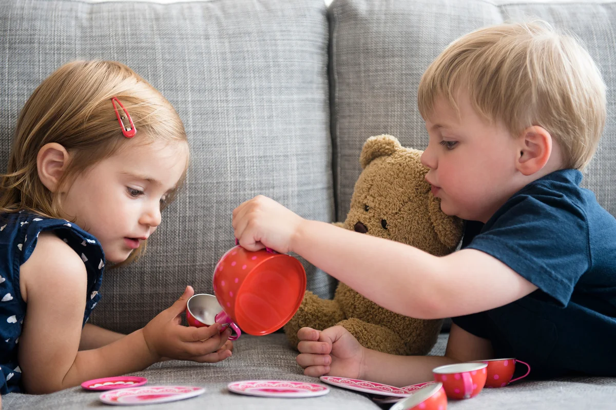 Brother and sister having tea party with teddy bear