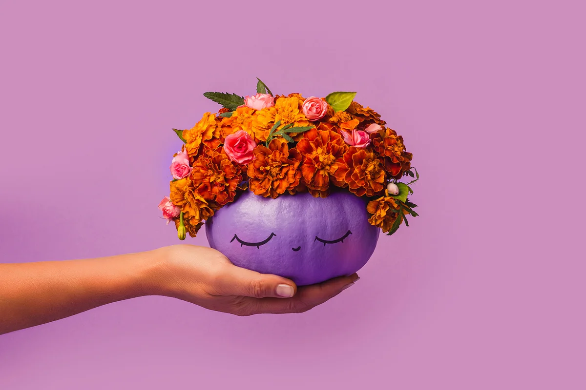 Purple pumpkin decorated with flowers in hand Halloween Concept