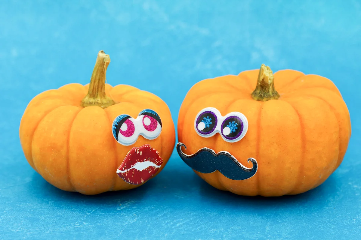 Two small pumpkins with sticker eyes, lips, mustache