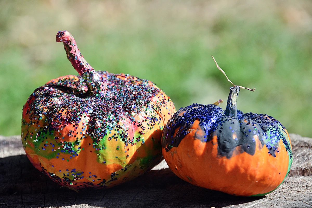 Two tiny pumpkins painted and sprinkled with glitter