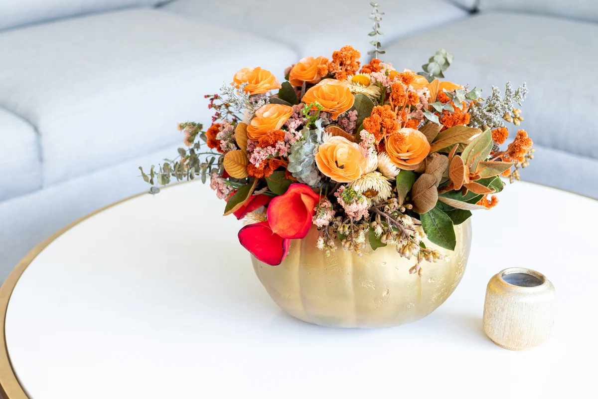 Floral arrangement of roses inside decorated pumpkin