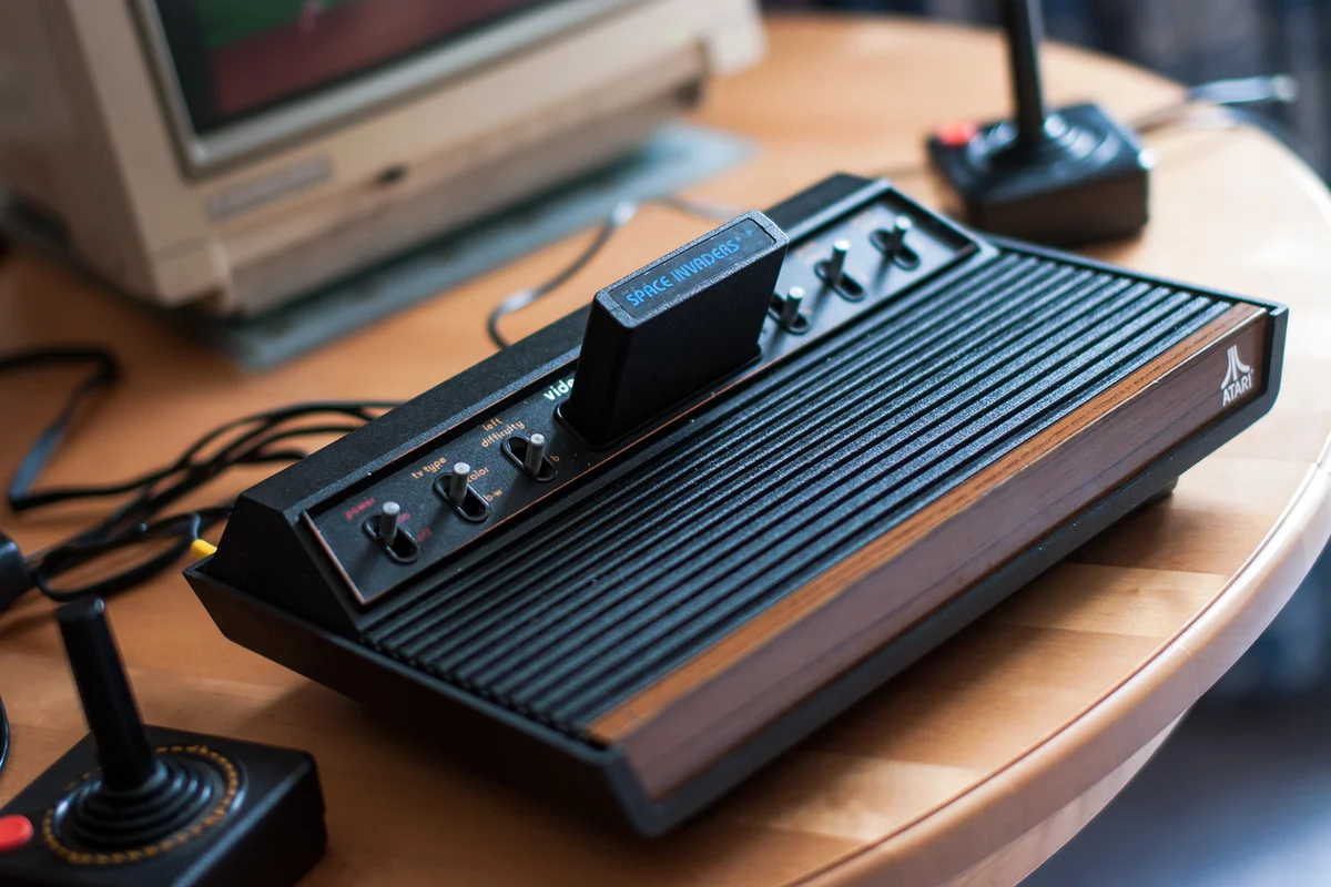 Atari 2600 VCS console, full view, with joysticks and Commodore 1084S monitor partially visible