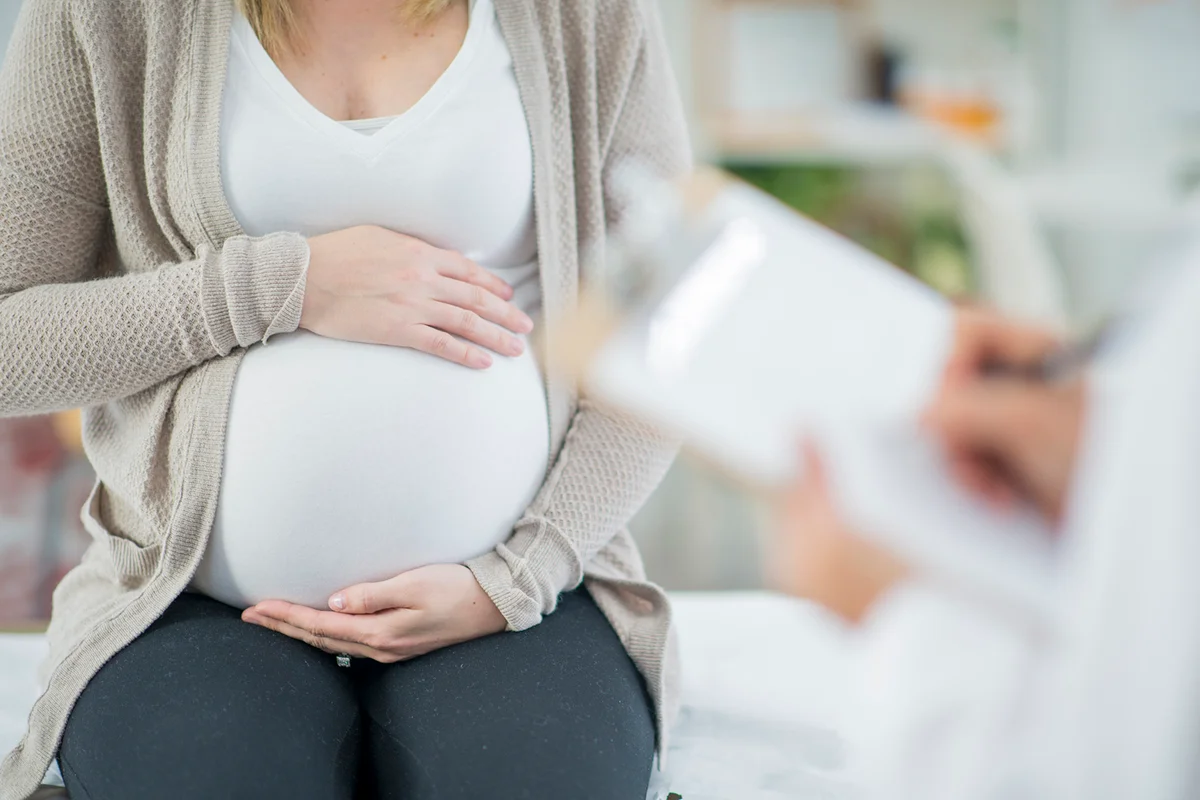 pregnant woman is indoors in a doctor's office