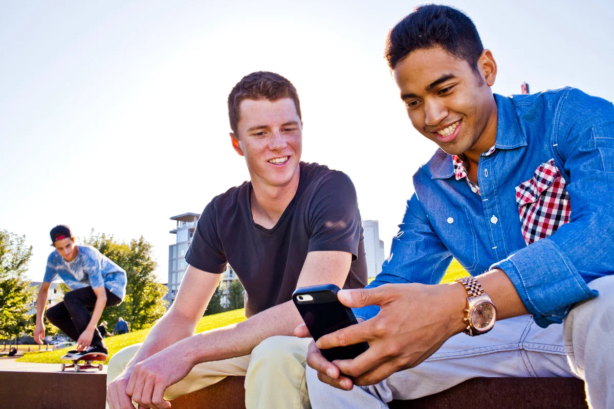 Guy texting with his friend next to him