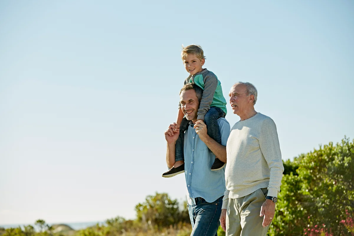 A father with his son on his shoulders, walking with grandpa