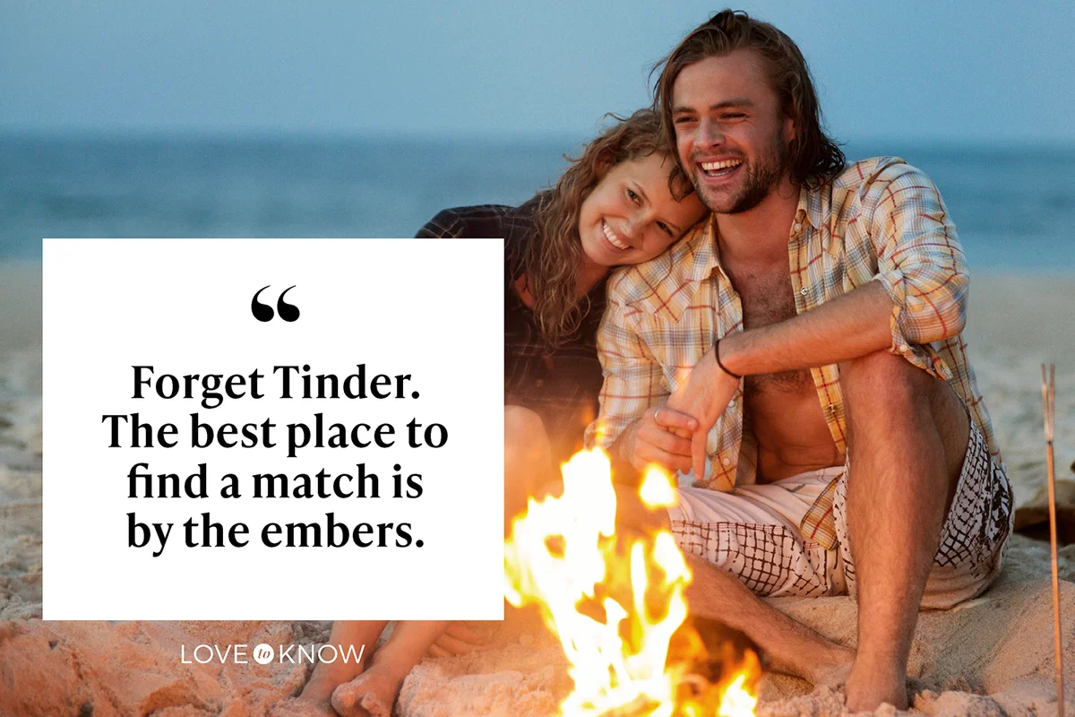 Couple sitting on sand by bonfire at beach