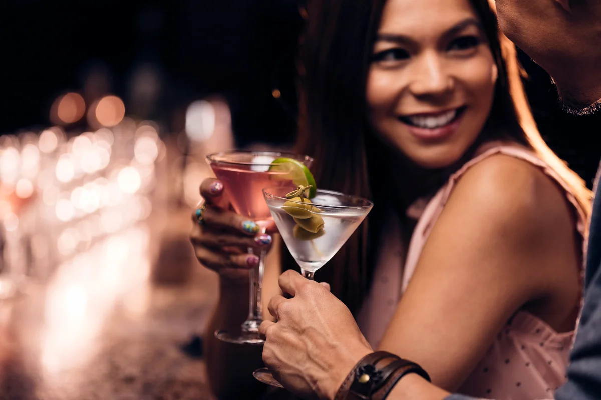 Smiling woman enjoying cocktail with friend at bar