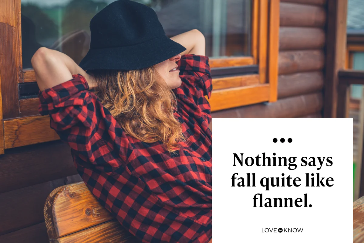 Young woman wearing a flannel shirt and a hat is relaxing on the porch of a log cabin