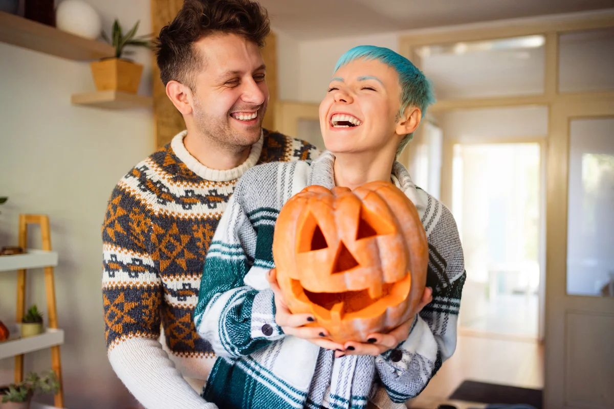 Young happy couple with Jack O' Lantern pumpkins