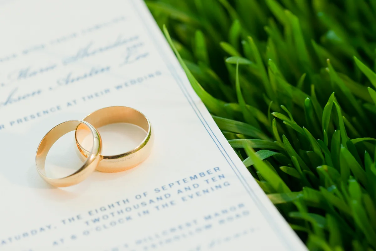 Wedding rings and marriage certificate on grass