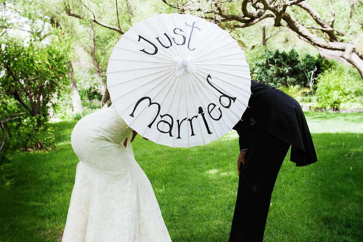 Bridal couple standing behind parasol