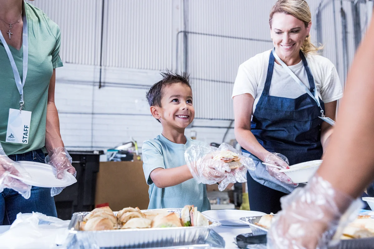 Young boy helps volunteer at the food drive