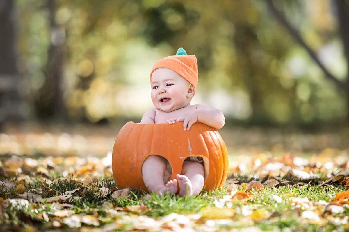 Naked baby boy in a pumpkin with orange hat