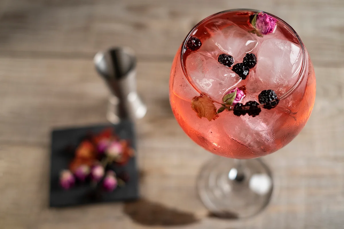 Pink gin tonic glass in top view with wooden base