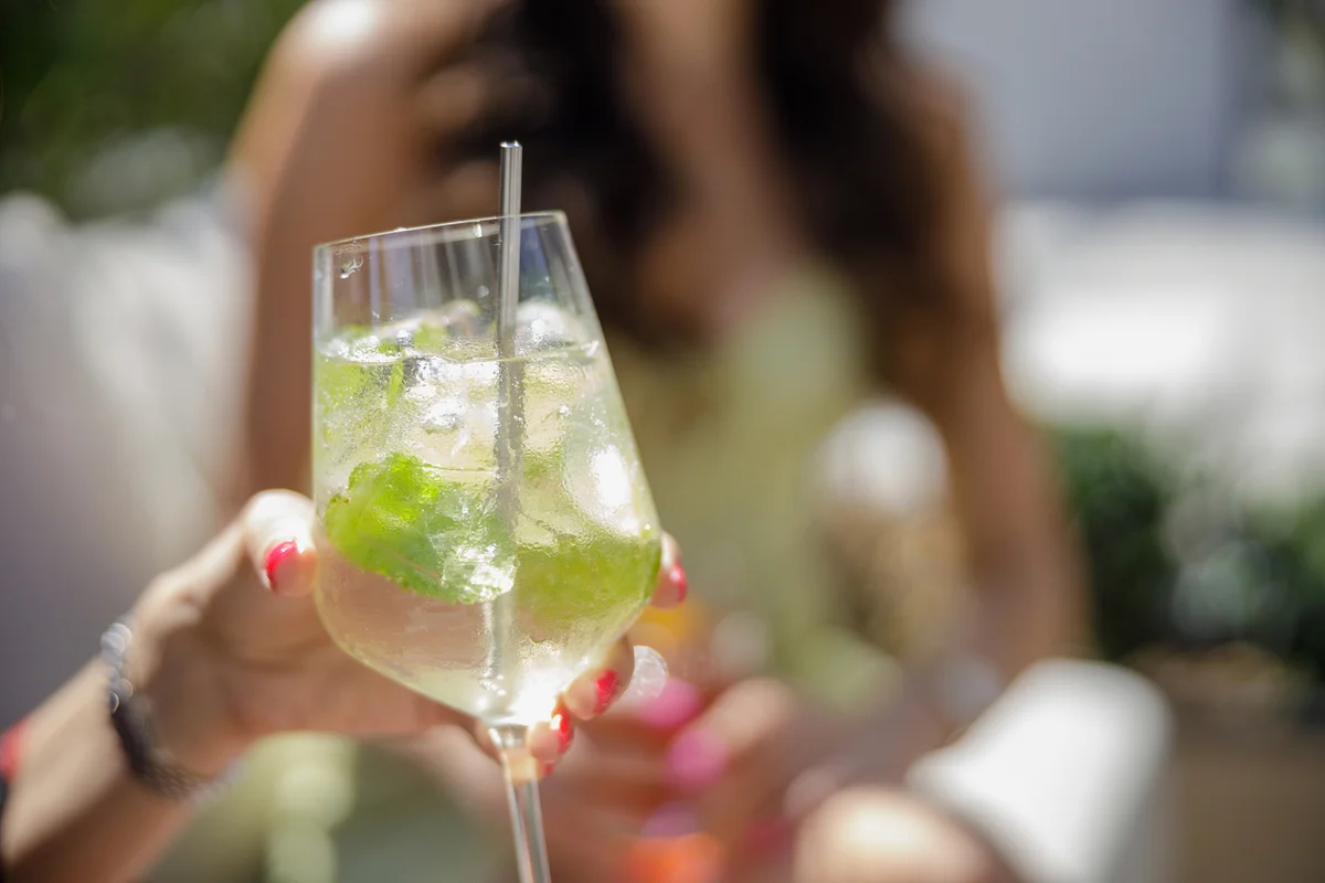 Holding a glass of cocktail on ice with stirring rod