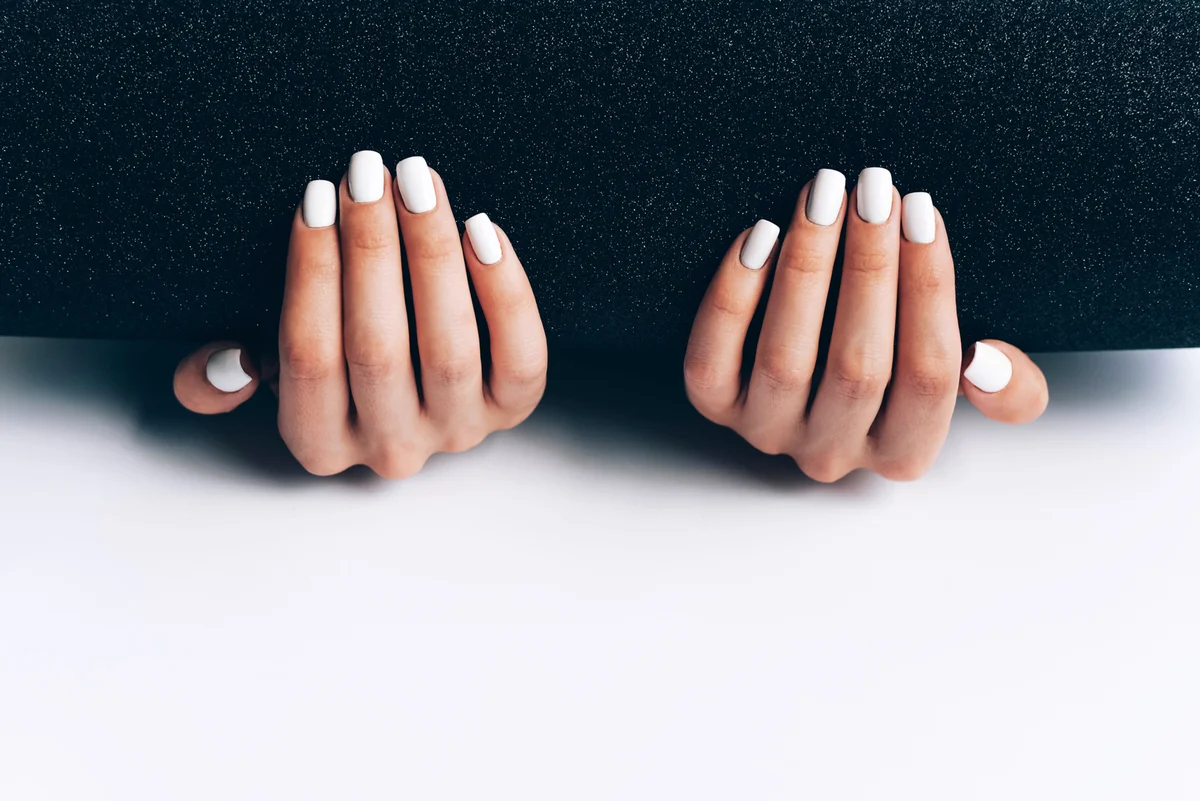 Female hands with white manicure on a black-white background
