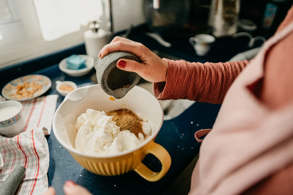 Woman chef pours species for the pumpkin cheesecake dough into a bowl
