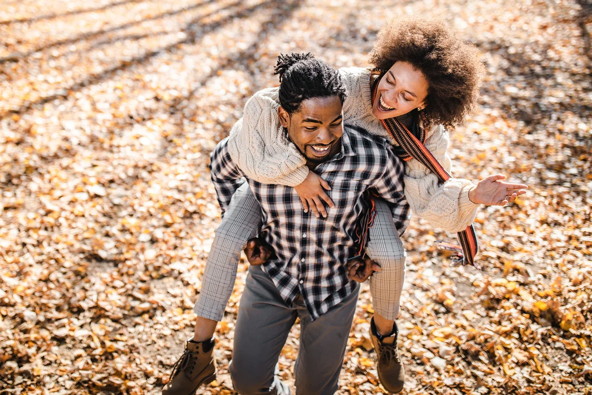 couple piggybacking in autumn at the park