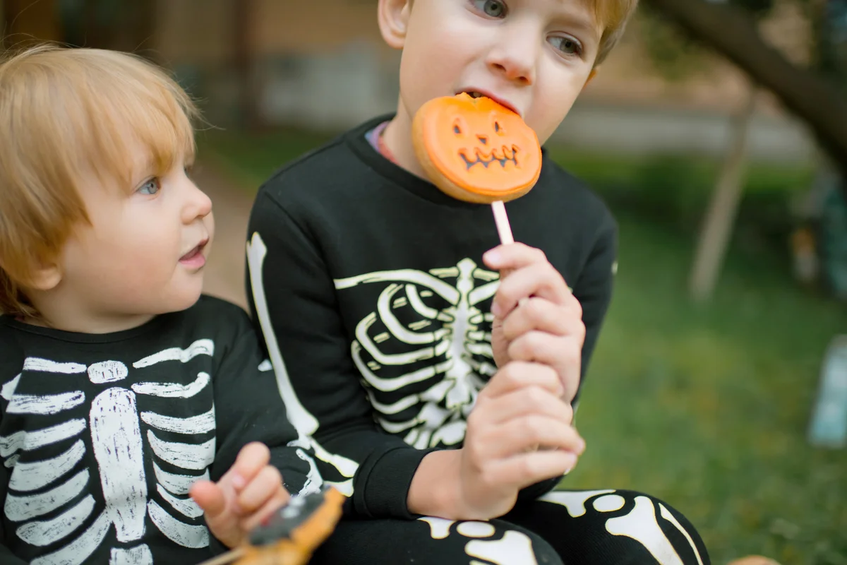 Kids dressed in skeleton costumes eating Halloween sweets