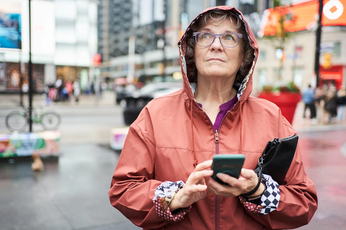 Mature woman with a phone looking up on an overcast day in the city