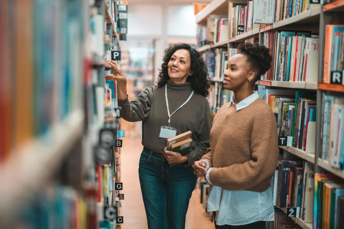 Librarian Escorting A Student In A Library