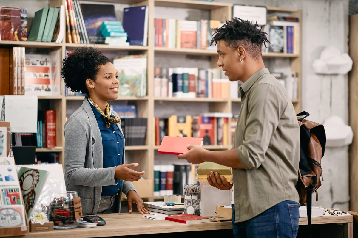 Student returning book to a librarian at university library
