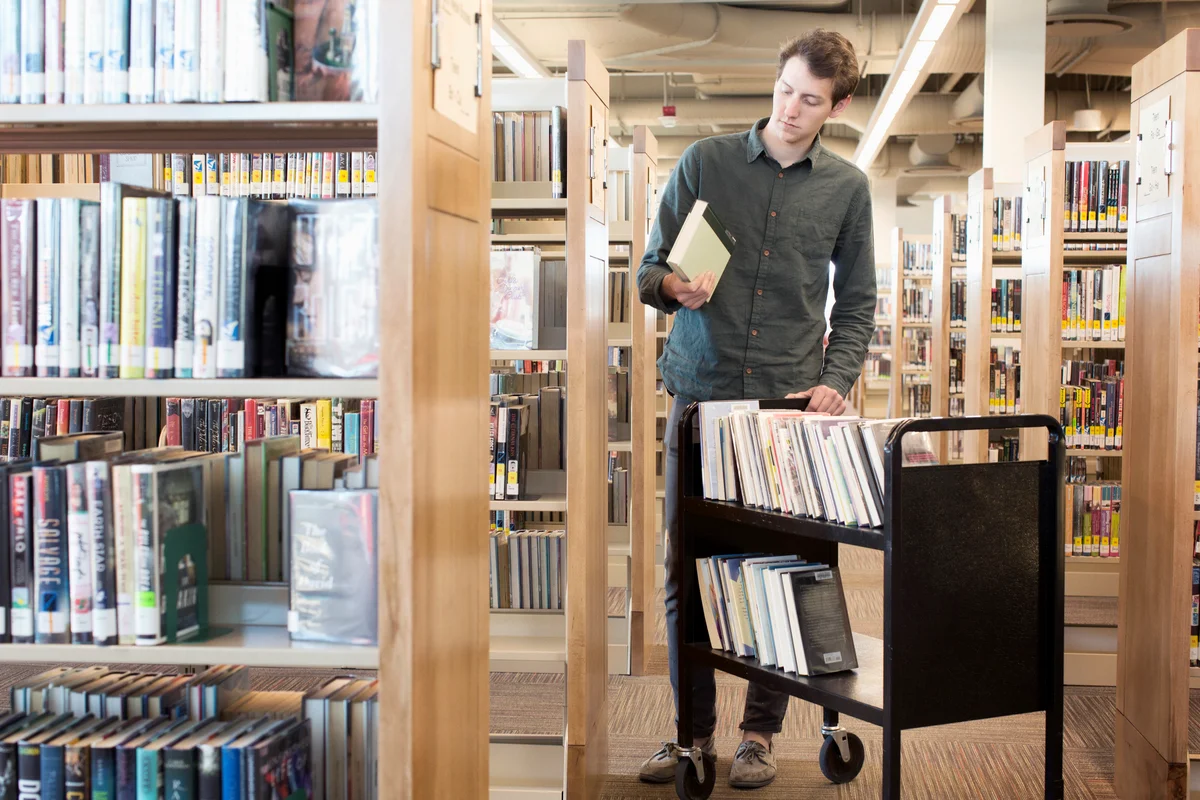 Librarian standing with book cart