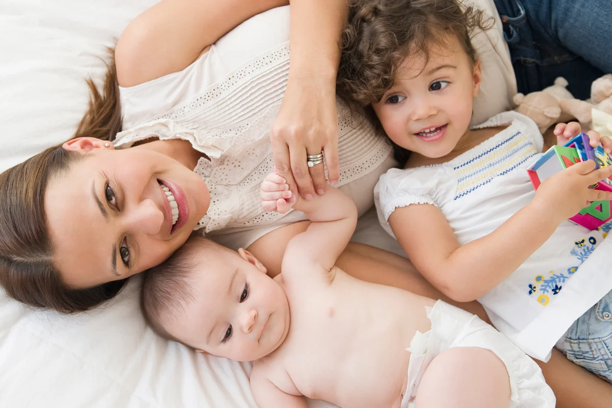 Mother laying on bed with daughters