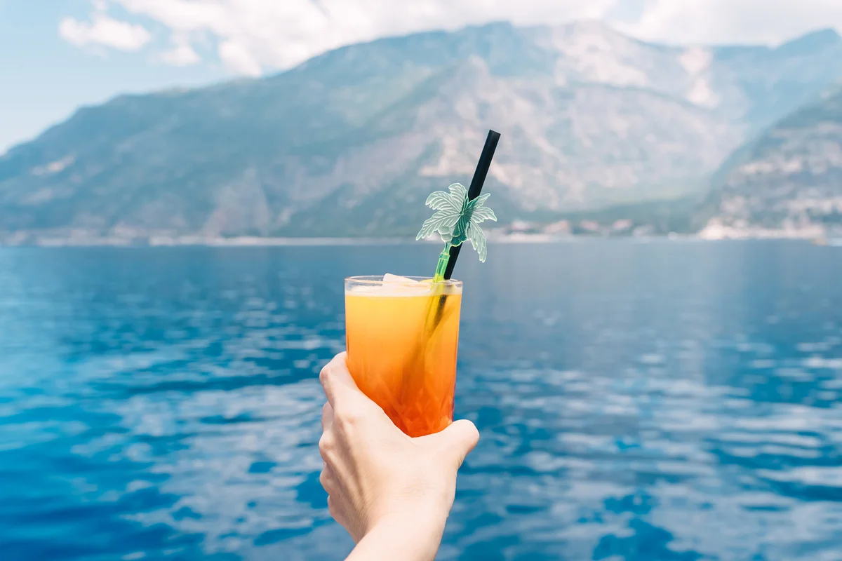 Cocktail Sex on the Beach in human hand on blue sea background