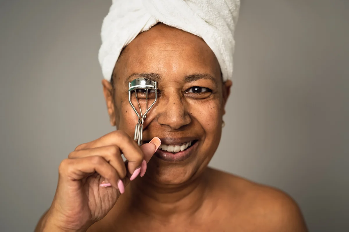 senior woman using eyelash curler
