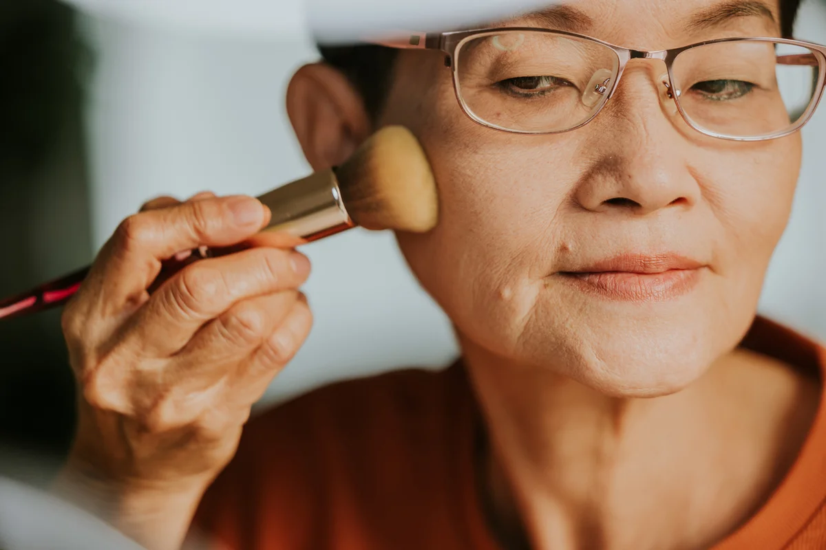 Happy senior adult woman showing some tips about brushing cheek