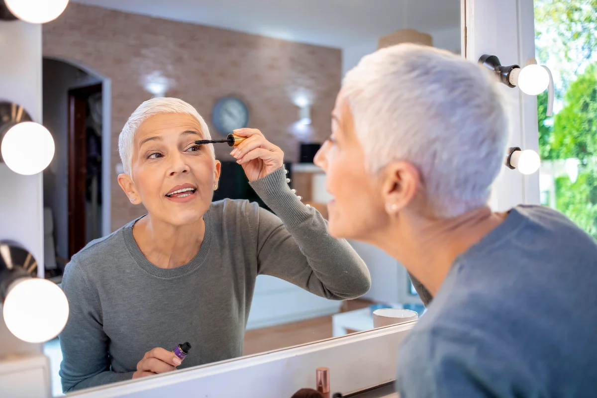 older woman applying eye makeup