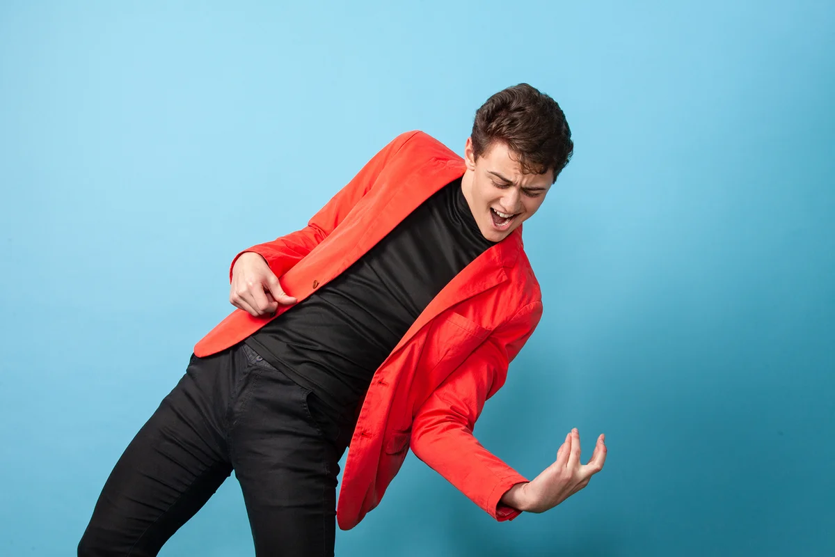 Studio portrait of a cheerful white teenager boy in a pink jacket