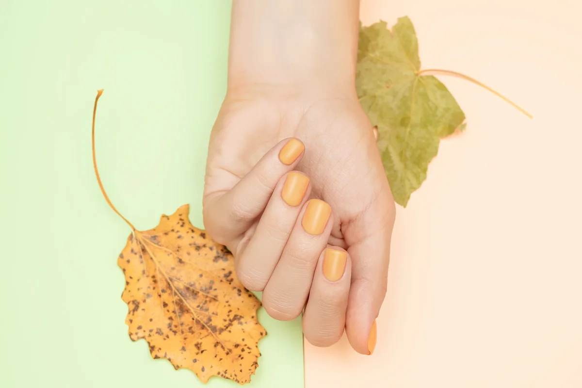 Female hand with mustard nail design