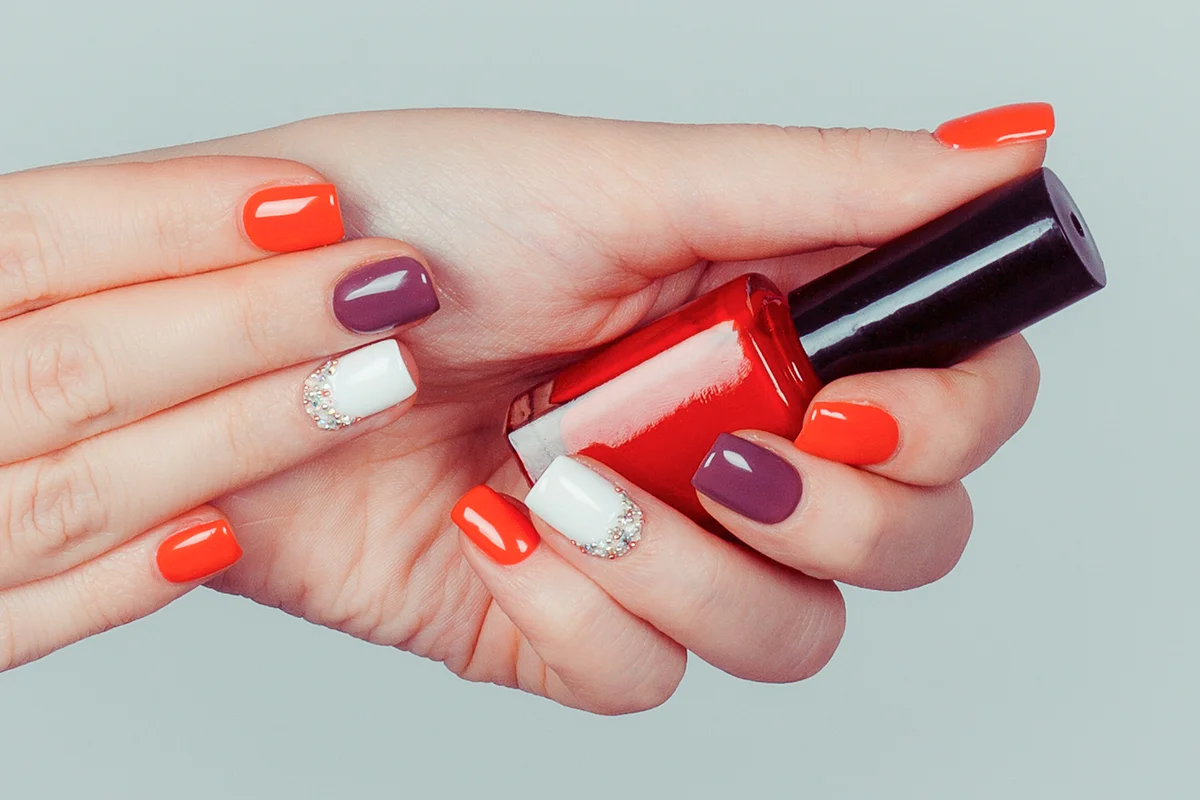 Hands with multi colored red white brown manicure