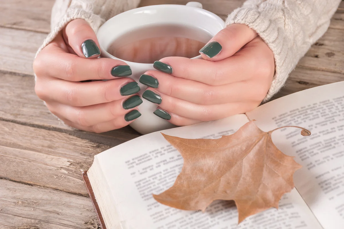 Woman hands in sweater with olive color manicure