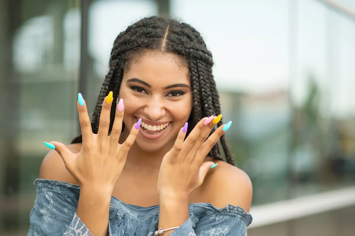 Young woman posing with rainbow nails