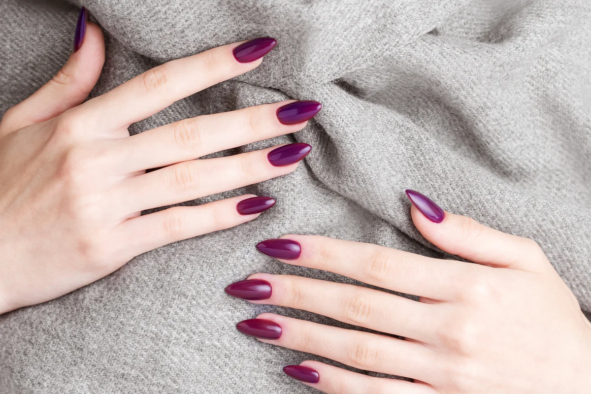 Young woman with dark purple manicure on nails