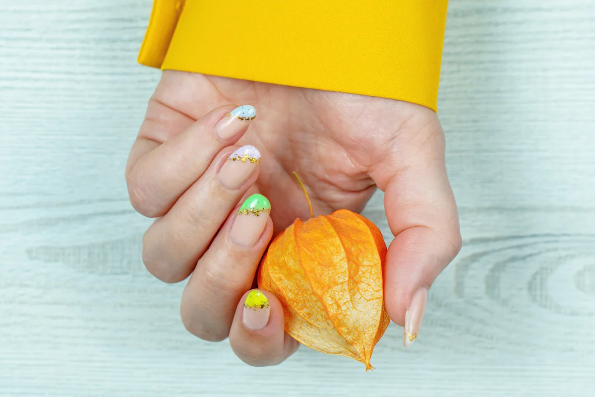 Woman with gold french tips holding a fruit