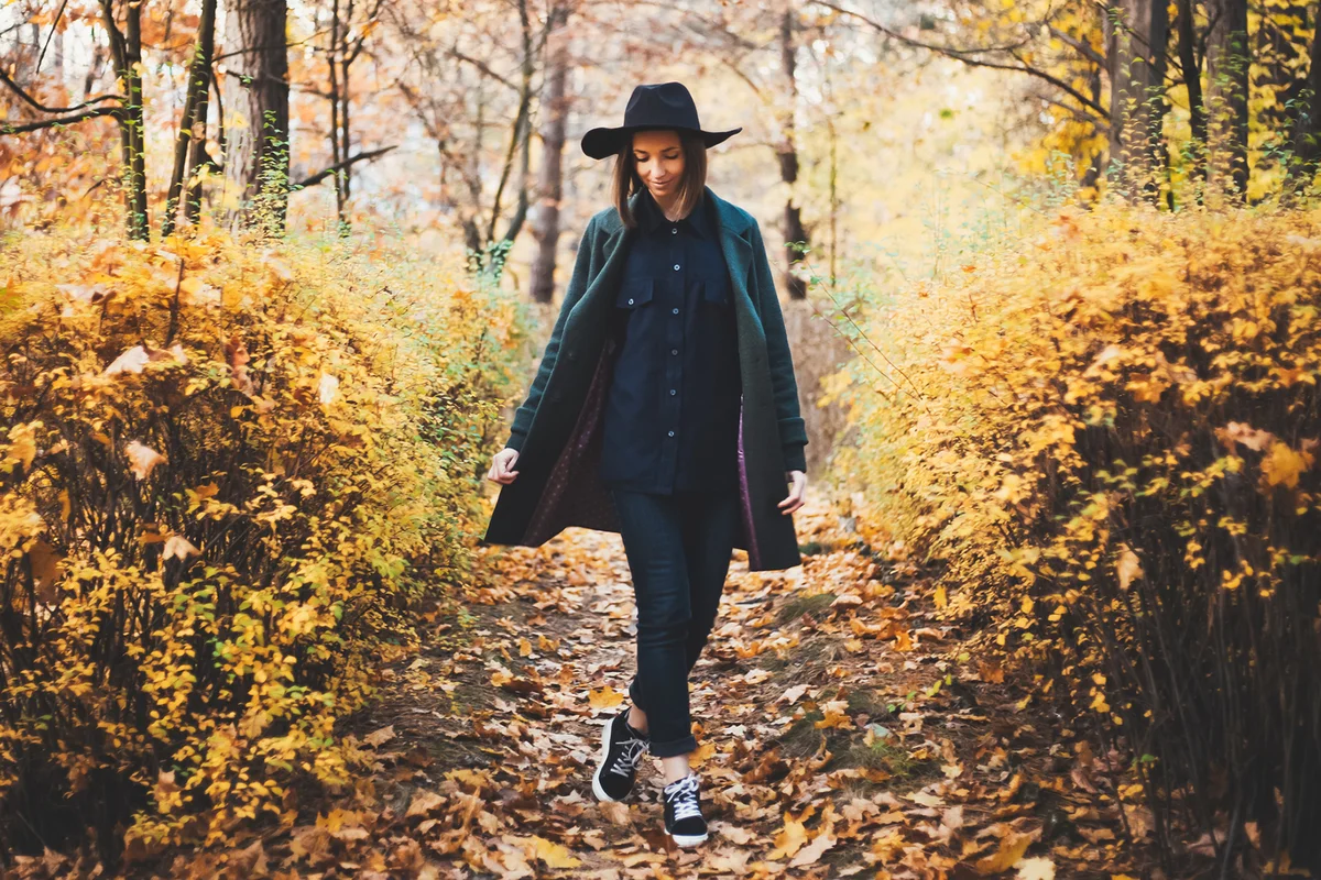 Girl in hat standing back at autumn forest