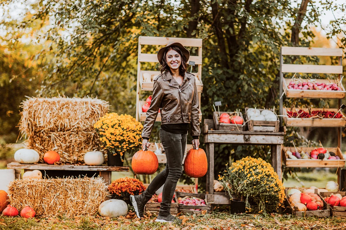 Happy woman holding pumpkins at market
