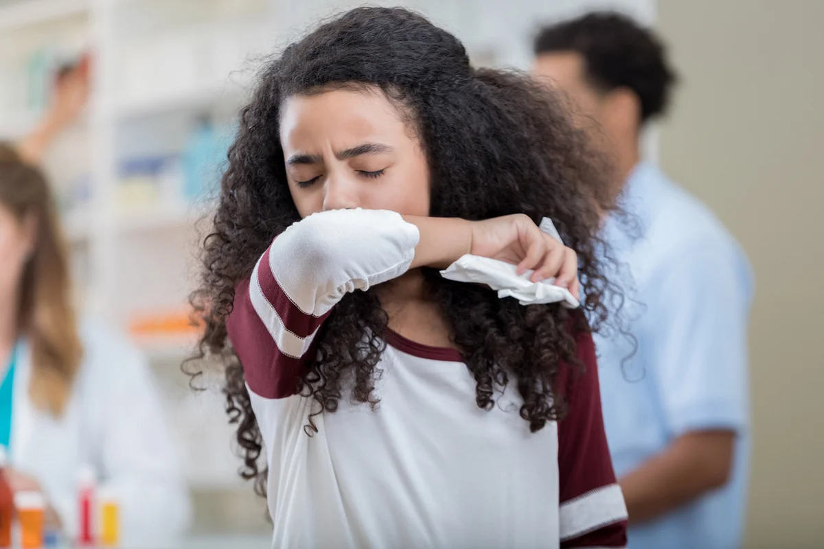 Mixed race preteen girl sneezes into her arm