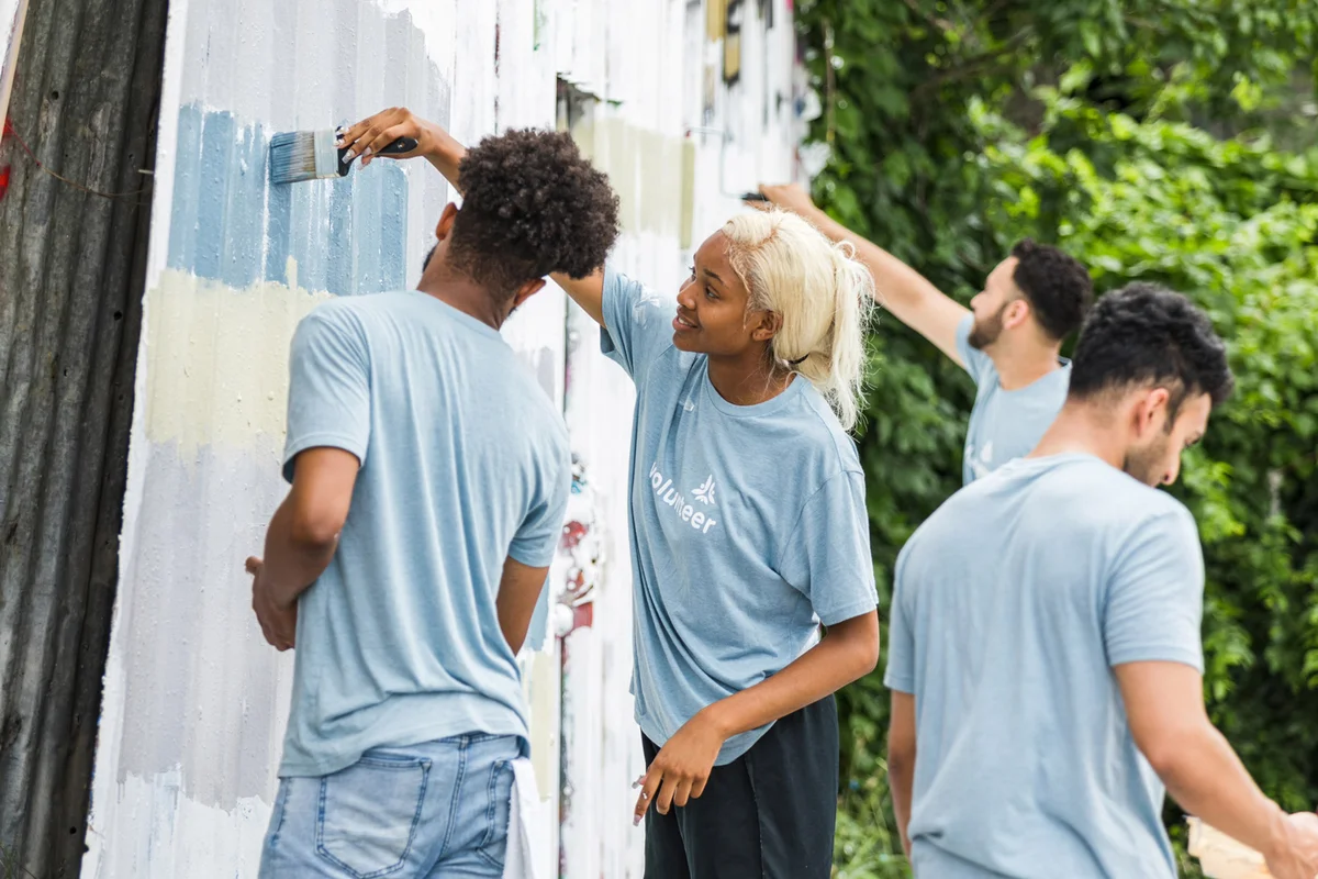 Young men and women painting building