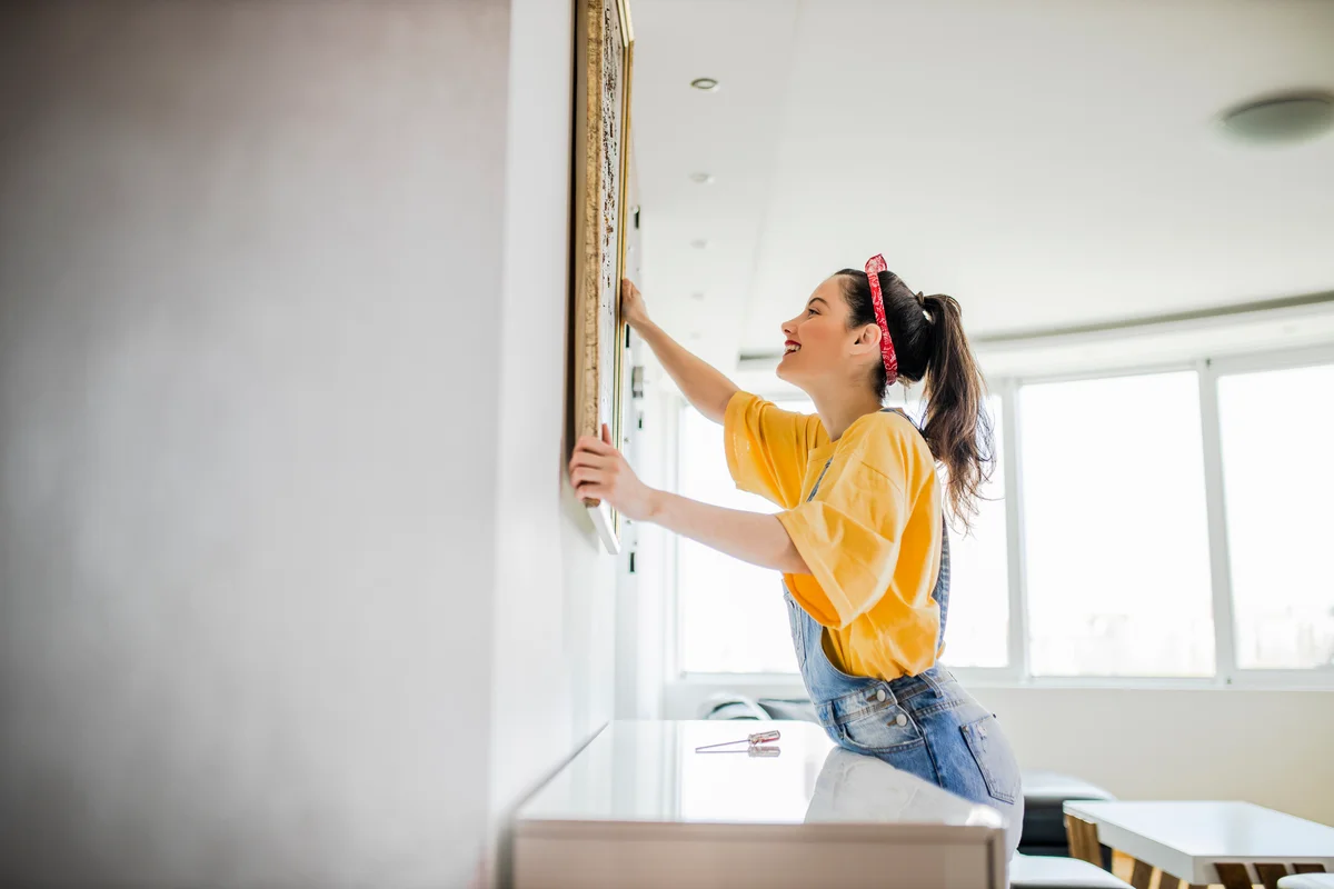 woman hanging a painting